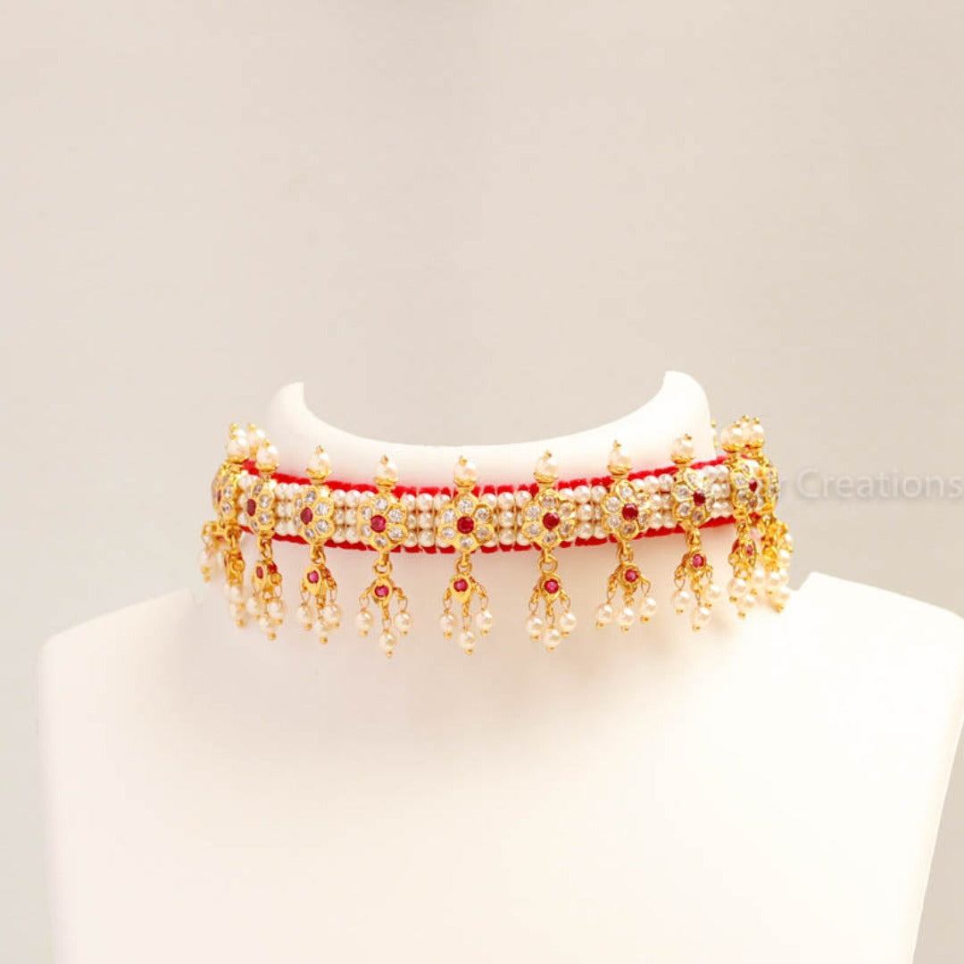 Beautiful chocker is embedded flower shape with white - pink colour stones and made from golden finish metal. This necklace is woven with good quality pearl beads and comes with adjustable thread so that you can fit it properly. It goes match with all type of ethnic sarees and dresses. It paired with matching earrings.